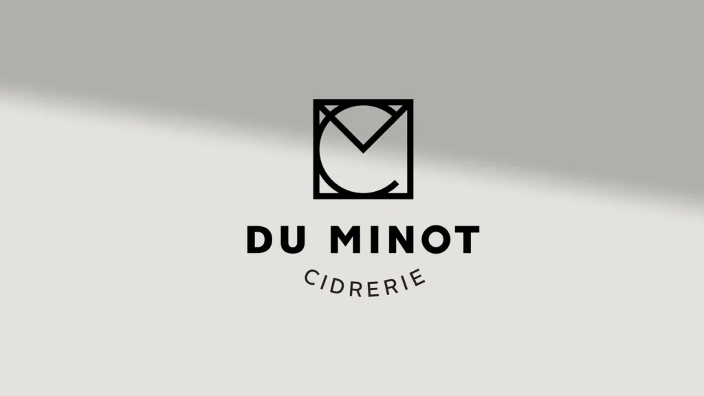 Logo de la Cidrerie du Minot, monogramme et nom, sur un mur gris