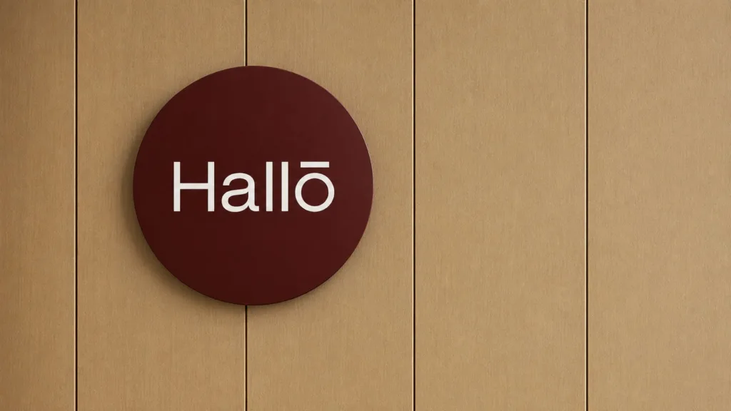 Enseigne ronde bordeaux Hallō sur un mur de bois