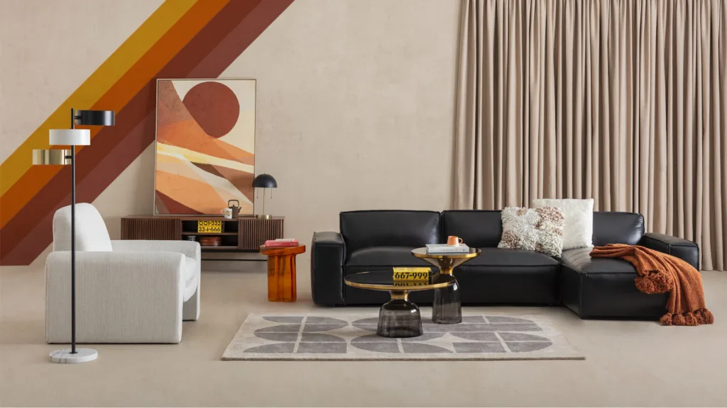 Salon avec canapé noir, fauteuil blanc et bandes orange au mur