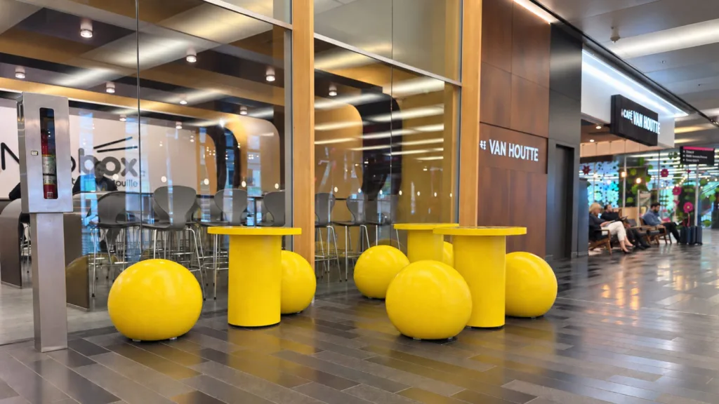 Tables et sièges ronds jaunes dans le hall vitré du Palais des congrès