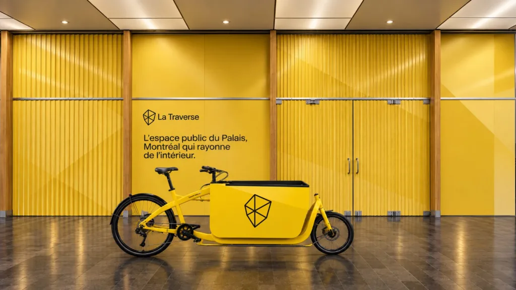 Mur jaune de La Traverse, l'espace public du Palais, avec un vélo-cargo jaune