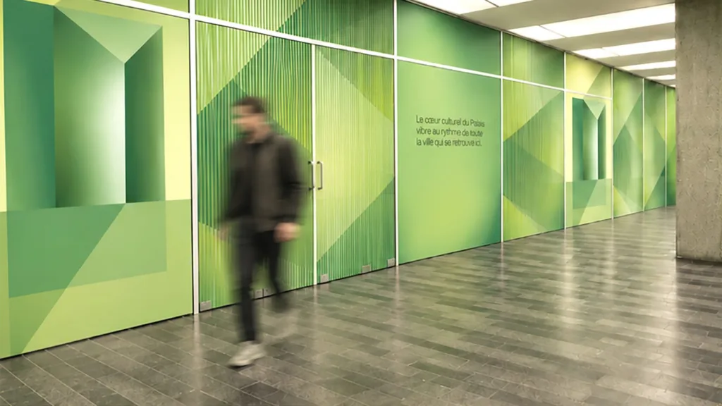 Corridor aux parois vitrées vertes, avec un passant